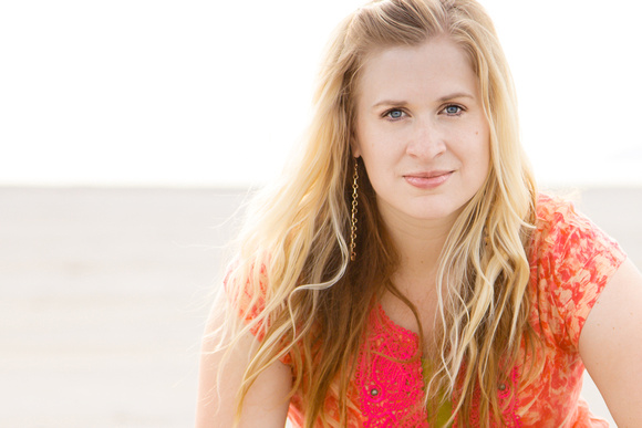 Whimsical portrait of a woman in a bright orange shirt on the beach